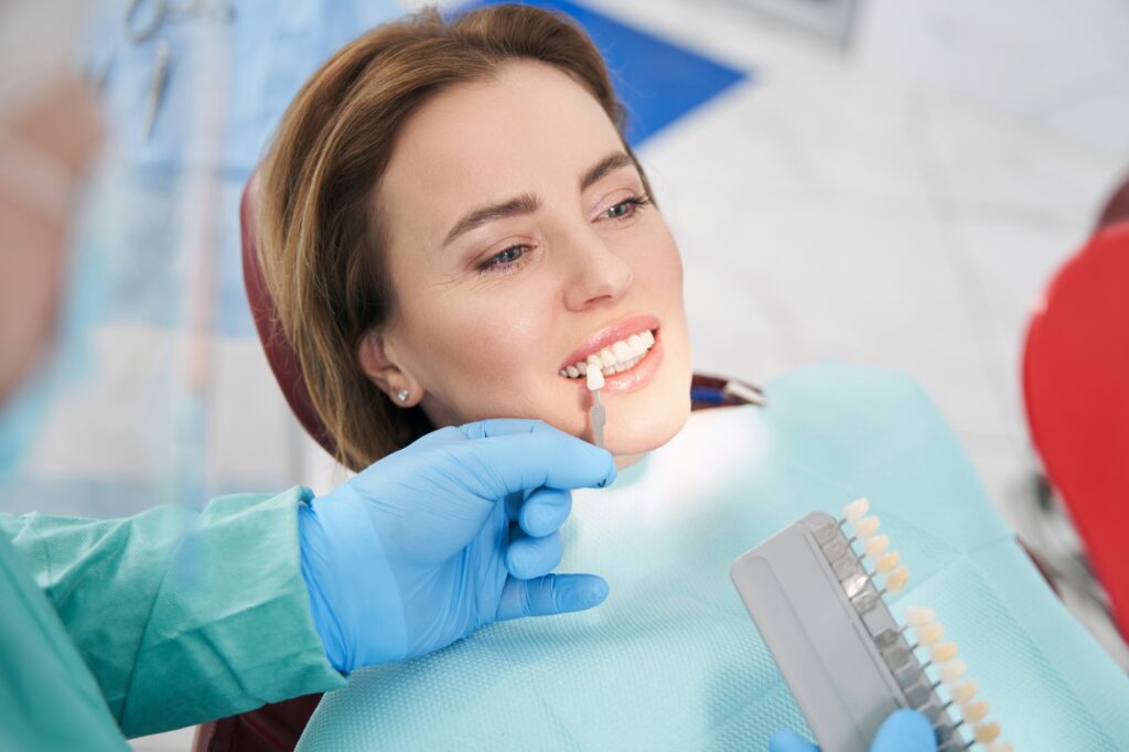 Doctor choosing color of woman teeth before dental treatment