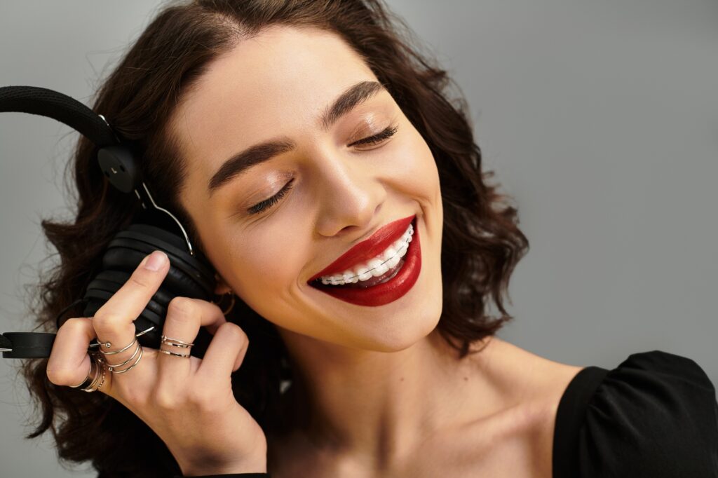 Enchanting young woman with braces enjoying music against a soft gray backdrop